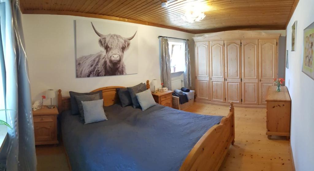 a bedroom with a bed with a cow on the wall at Reithamer Bergfensterl in Warngau