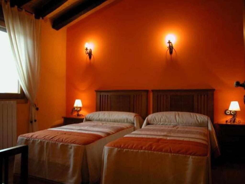 2 letti in una camera con pareti arancioni di Apartamento Miralrio a Milagro