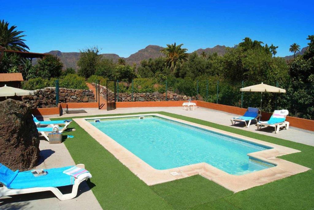 a swimming pool with two lawn chairs and two lawn chairs at Casa Rural La Fuente de la Flora in Santa Lucía