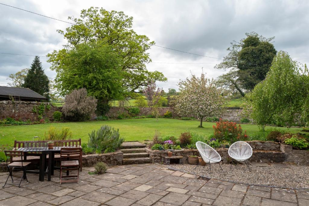 a patio with a table and chairs in a garden at Little Underhill in Oswestry