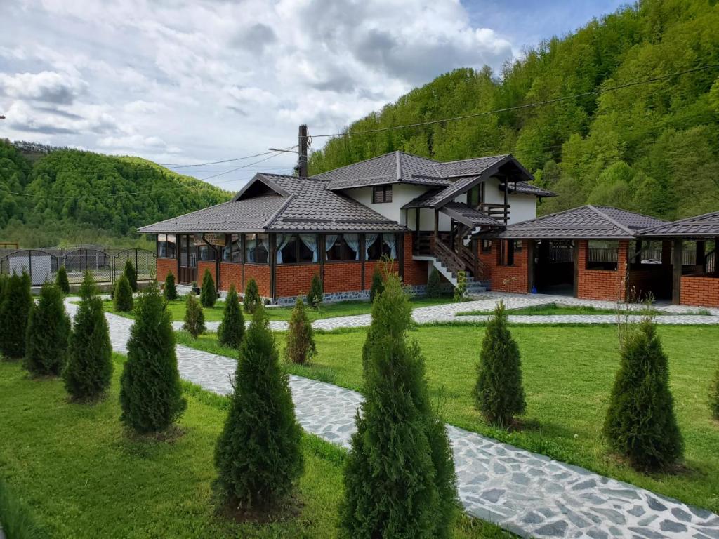 a house with a garden in front of it at Pensiunea Perla Râușor in Rîuşor