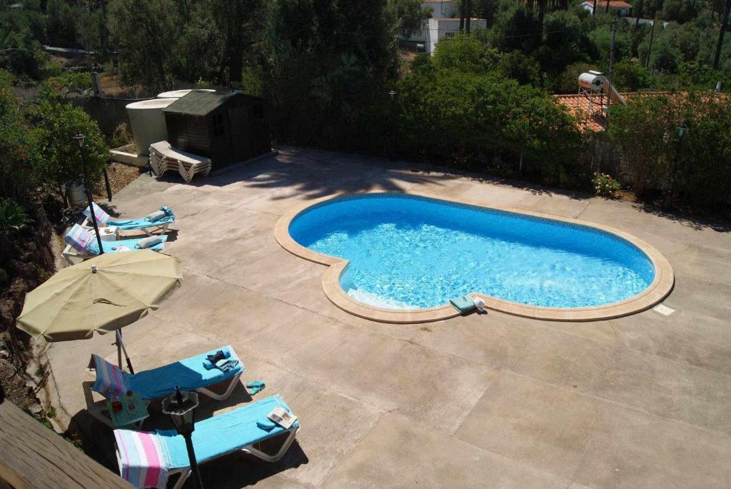 a swimming pool with two chairs and an umbrella at Casa rural El Olivar - La Oliva in Santa Lucía