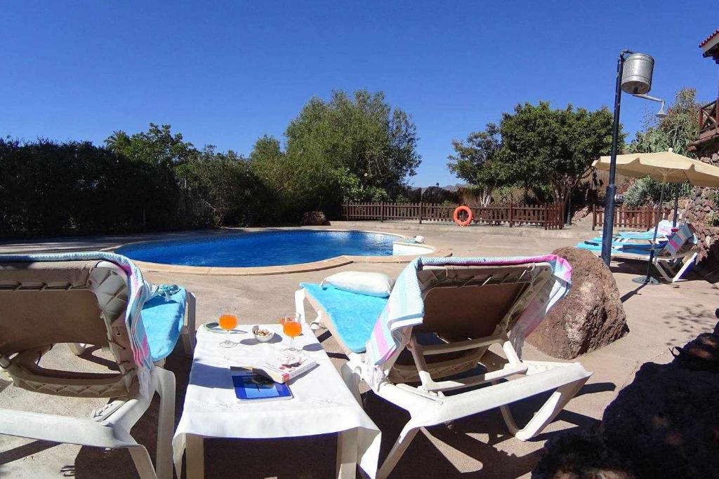 2 chaises longues et une piscine avec une piscine dans l'établissement Casa rural El Olivar La Molienda, à Santa Lucía