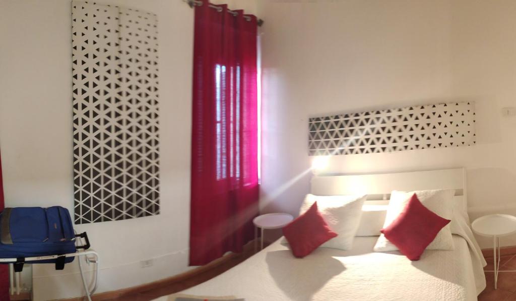 Casetta di Myra في باري: غرفة نوم بسرير ومخدات حمراء وبيضاء