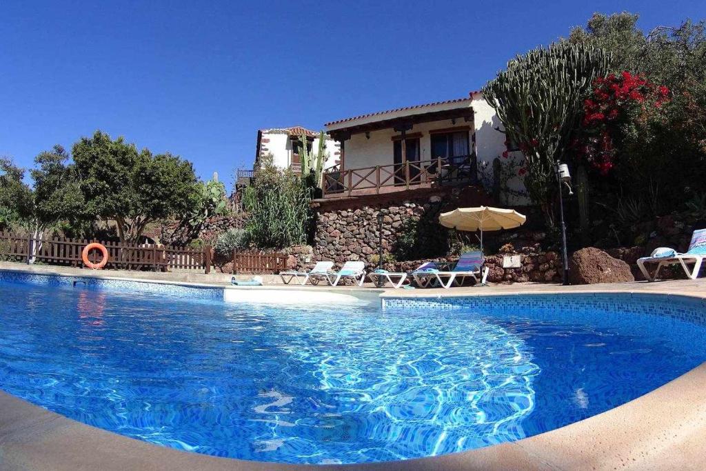 uma grande piscina azul com uma casa ao fundo em Casa rural EL Olivar El Orujo em Santa Lucía