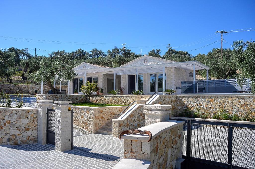 a house with a stone wall and a fence at Paxos Luxury Living Junior Suites in Gaios