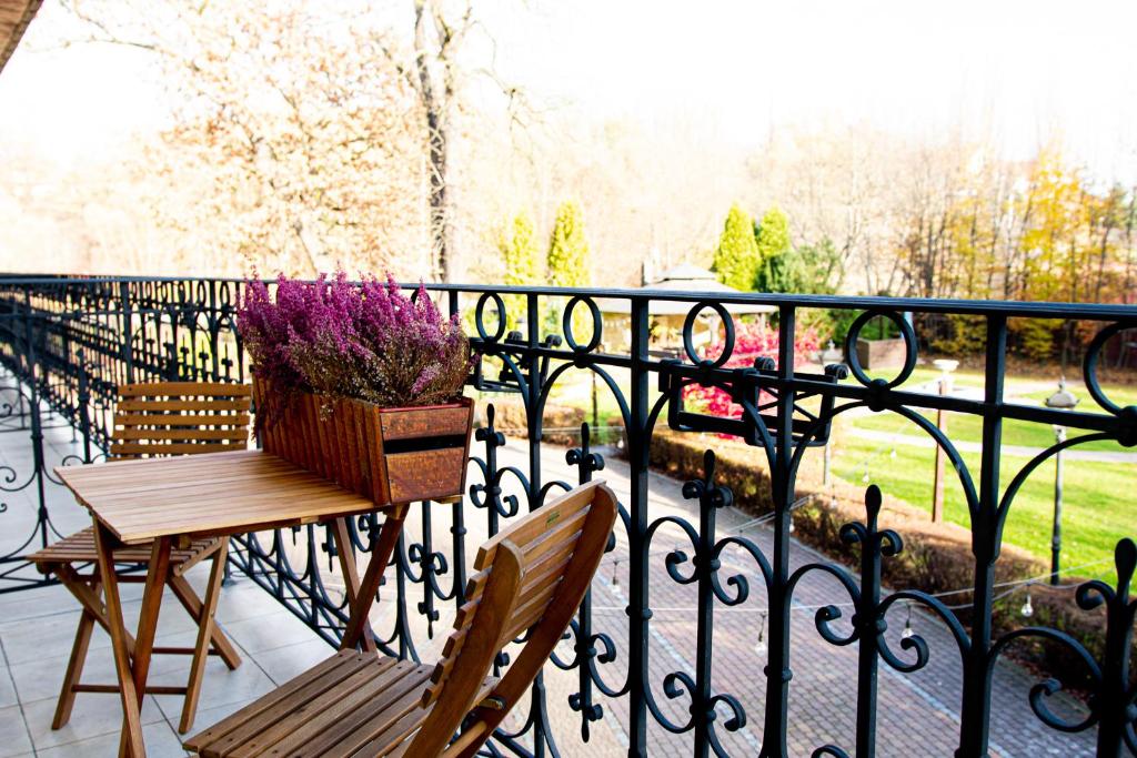 bistro-style balcony with wooden table and chairs, planter of purple flowers, ornate iron railing