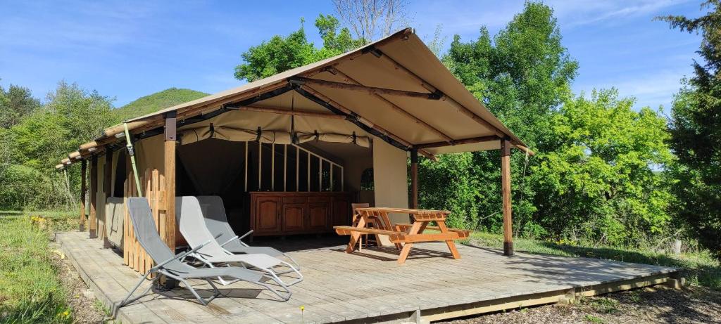 einen Pavillon mit einem Tisch und Stühlen auf einer Holzterrasse in der Unterkunft Camping des vignes in Dun