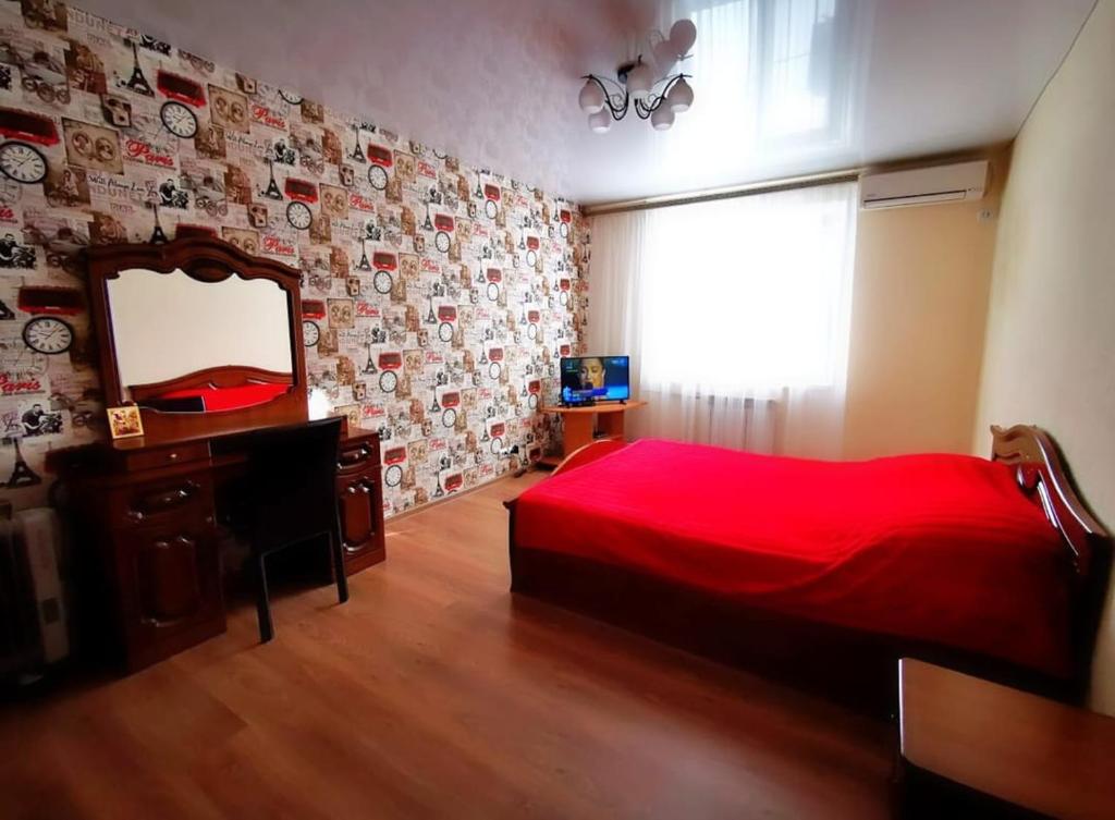 エッセントゥキにあるКвартира ул. Кисловодскаяのベッドルーム(赤いベッド1台、鏡付)
