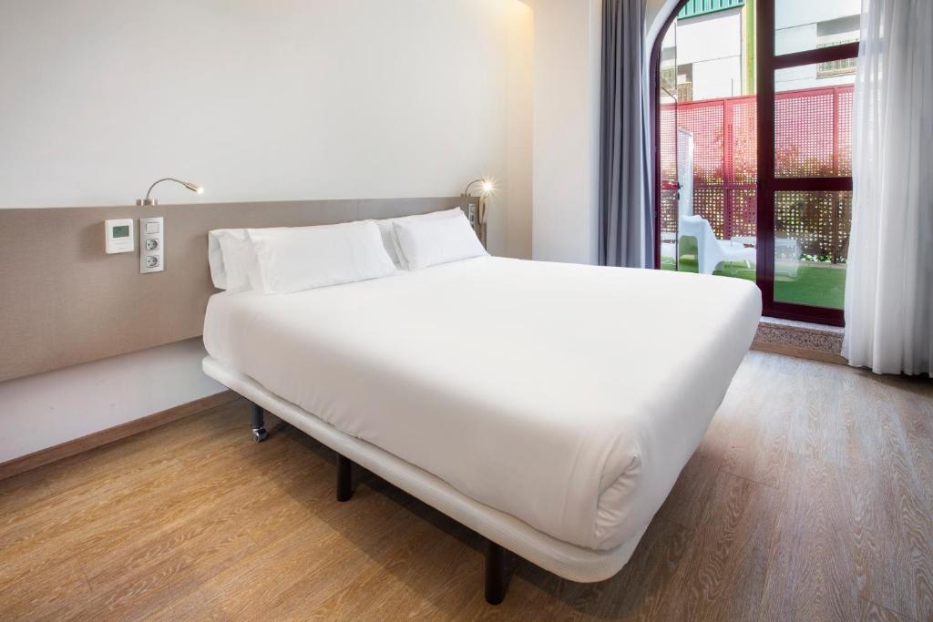 1 cama blanca grande en una habitación con ventana en B&B HOTEL Madrid Fuenlabrada, en Fuenlabrada