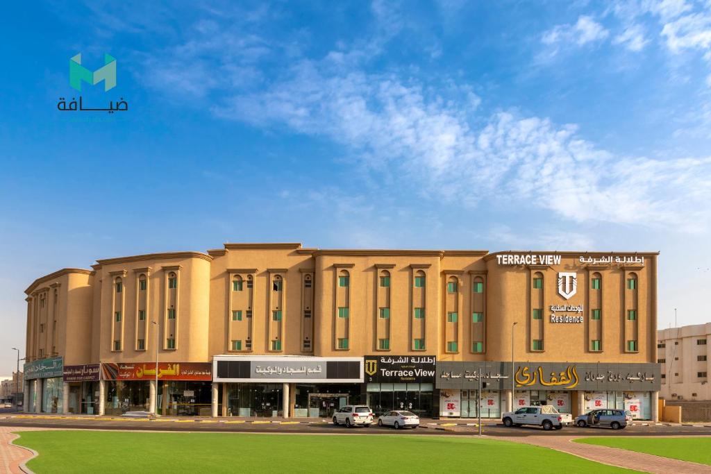 a large building with cars parked in a parking lot at Terrace View 3 - Hotel Apartments in Dammam