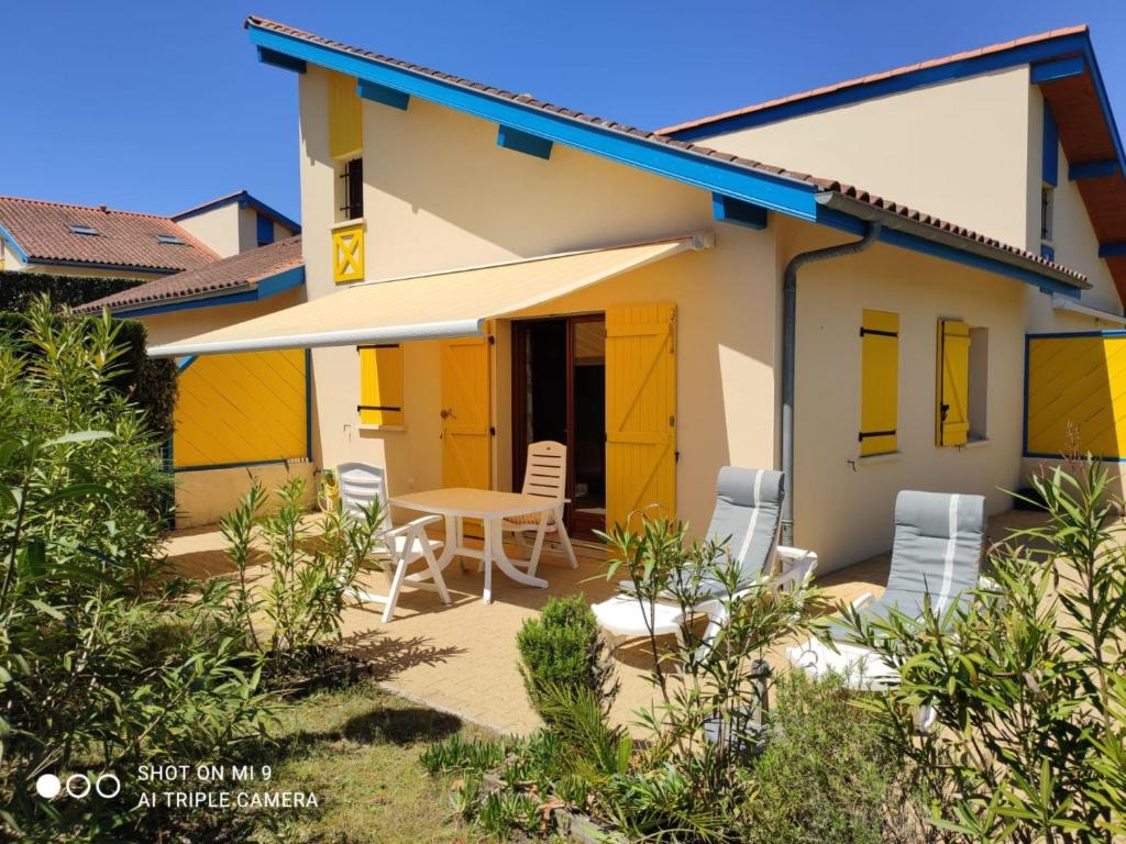 a house with yellow doors and a table and chairs at Village Océlandes in Saint-Julien-en-Born