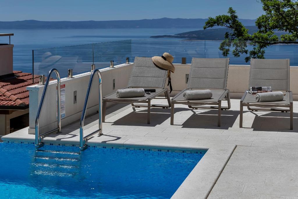 a teddy bear sitting in a chair next to a swimming pool at Villa Prestige in Baška Voda