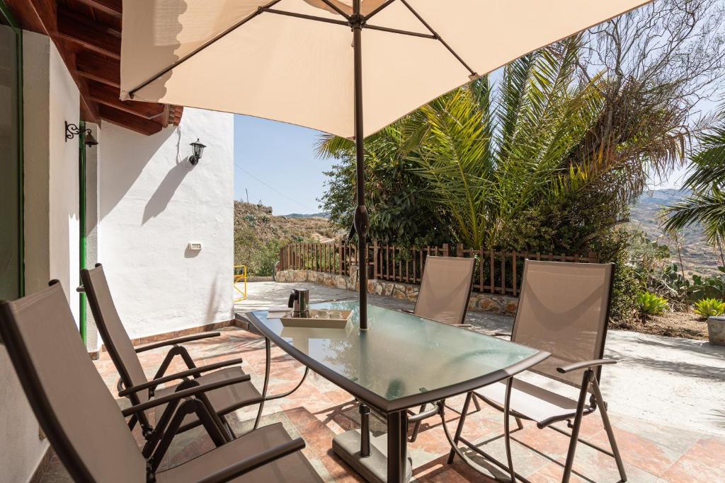 un patio con mesa, sillas y sombrilla en Sunset Views Terrace 2BR Cave House - Parking, en Santa Brígida
