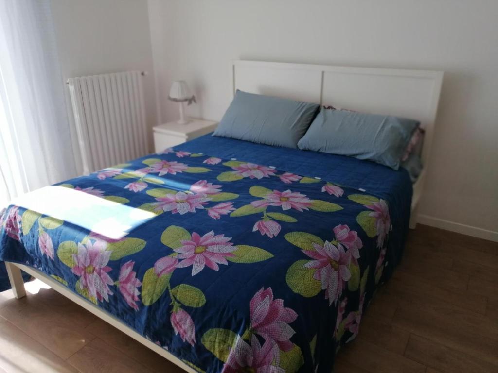 uma cama com um edredão azul com flores em Casa Posa em Bari