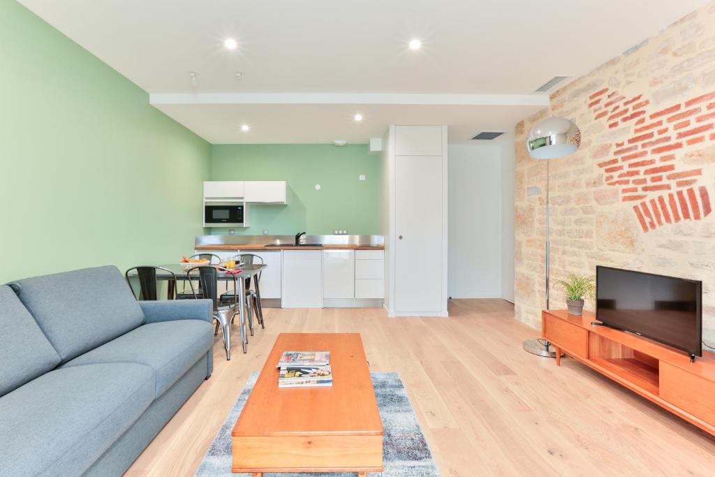 a living room with a blue couch and a brick wall at VILLA14 in Dijon