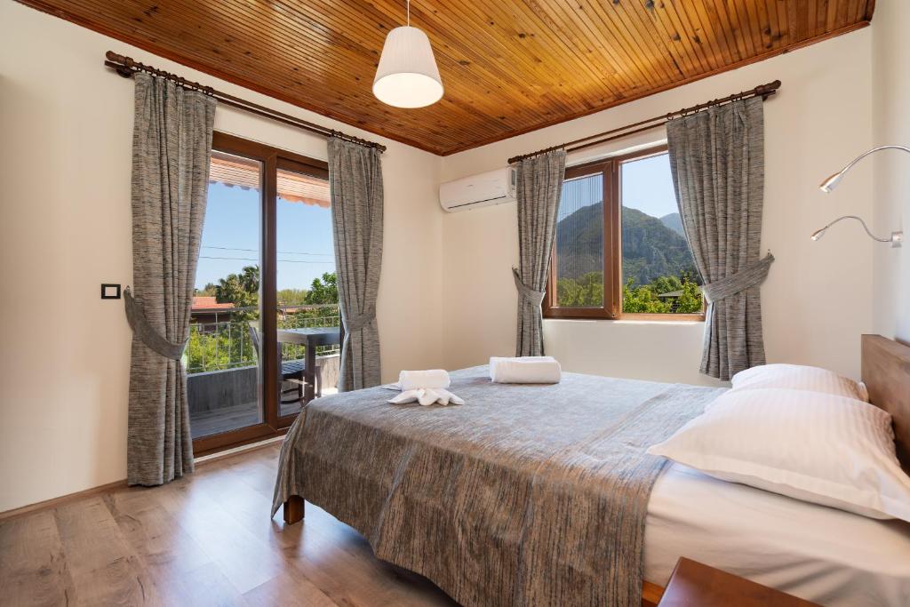 a bedroom with a large bed with windows and a balcony at Ayris Hotel Çıralı in Cıralı