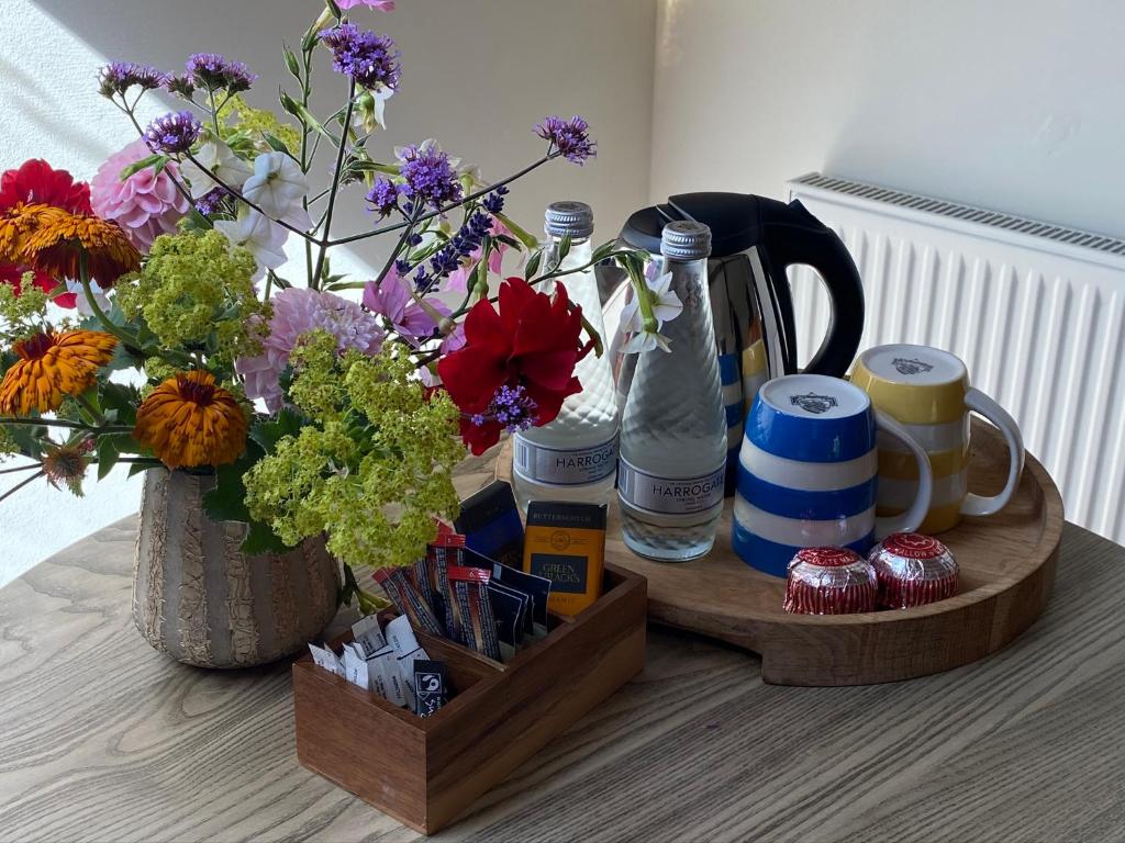 uma bandeja de madeira com flores e garrafas sobre uma mesa em Burrator Inn em Yelverton