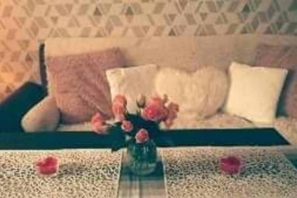um sofá com almofadas e um vaso de flores sobre uma mesa em Nowoczesne mieszkanie blisko natury i sklepu Biedronka em Karpacz
