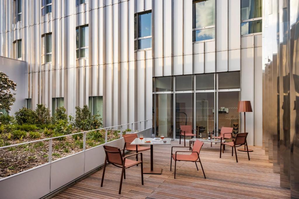 - un balcon avec des tables et des chaises en face d'un bâtiment dans l'établissement OKKO Hotels Lille Centre, à Lille