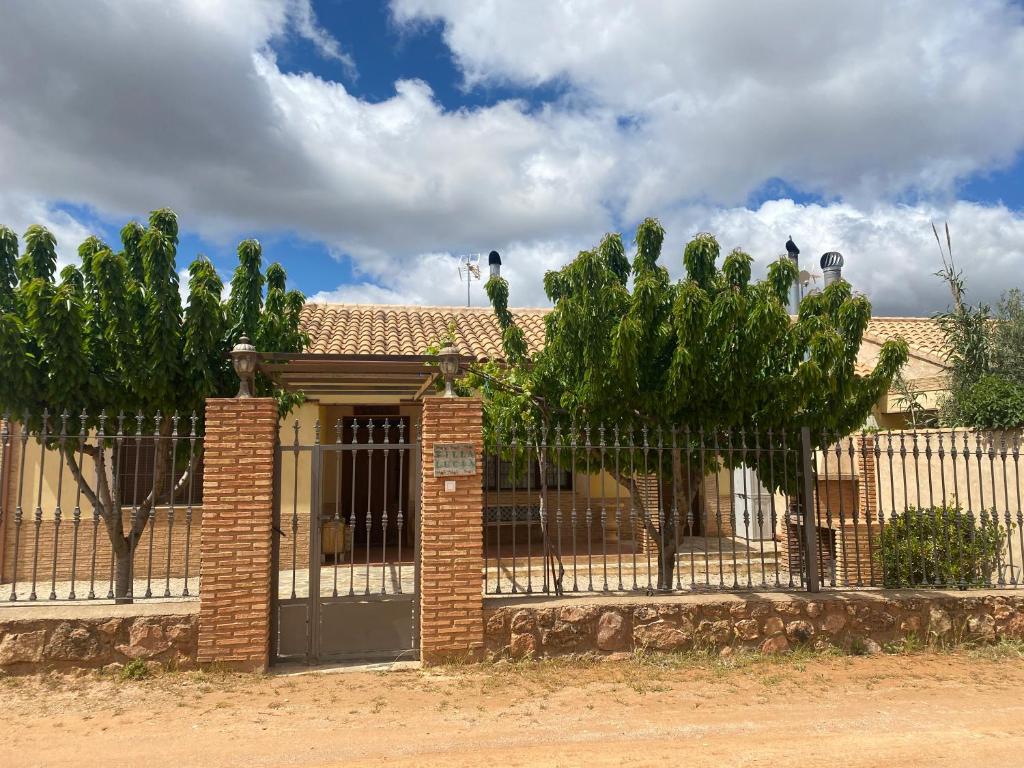 a fence in front of a house with trees at Casa Rural Villa Lucia in Ossa de Montiel