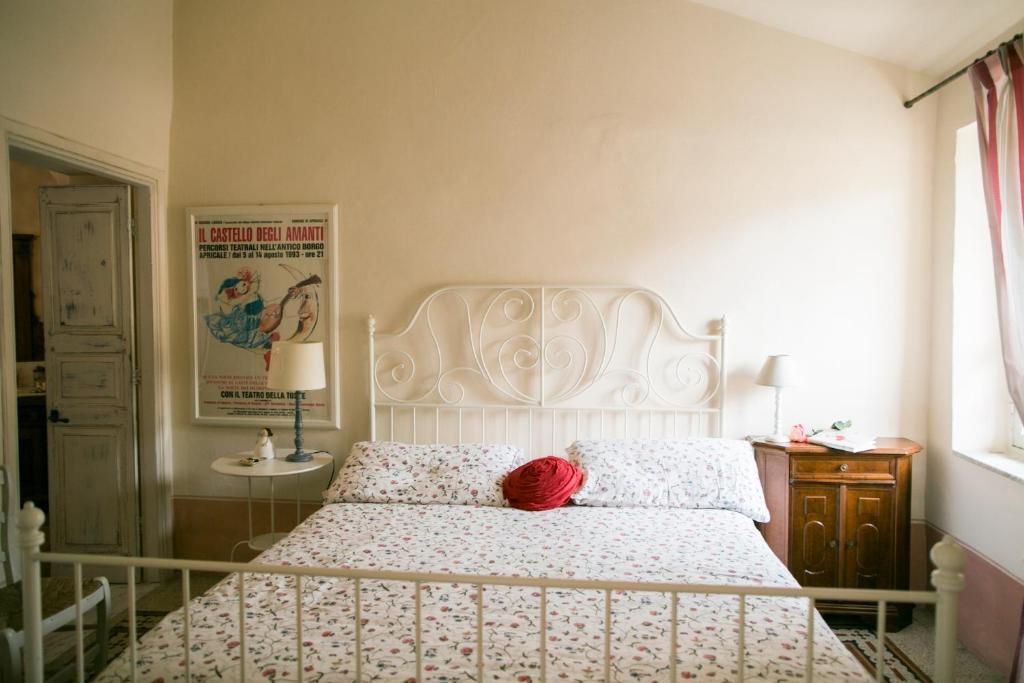 a bedroom with a white bed with a red hat on it at BB Le Gemme in Dolceacqua