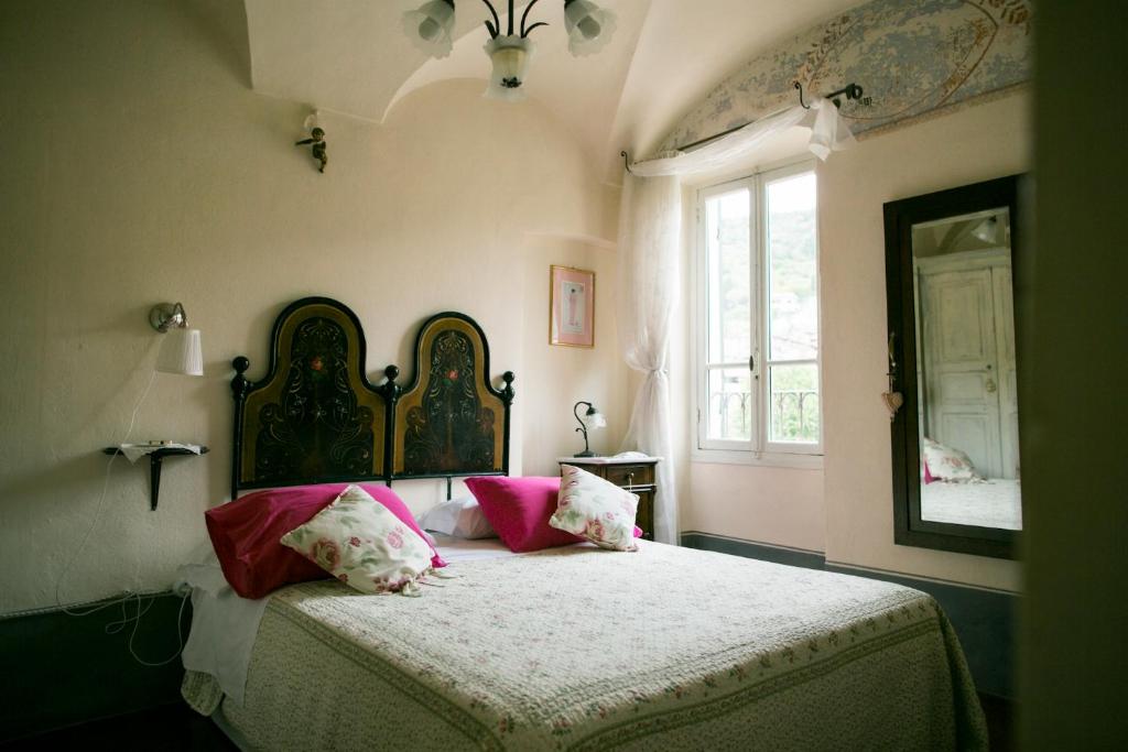 a bedroom with a bed with pink pillows and a window at BB Le Gemme in Dolceacqua