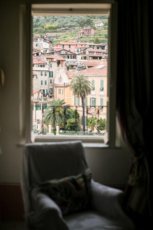 a window with a couch looking out at a city at BB Le Gemme in Dolceacqua