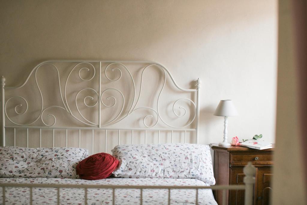 a bed with a white headboard and a red pillow at BB Le Gemme in Dolceacqua