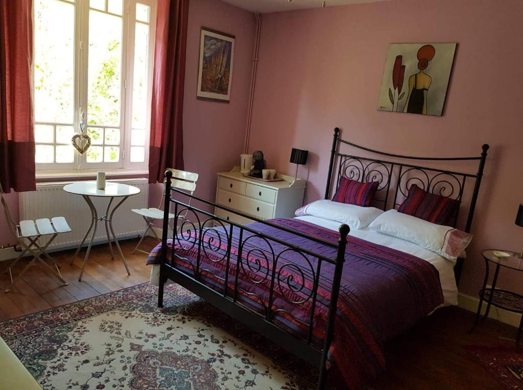 a bedroom with a bed and a table and windows at Les Charrons in Ségur-le-Château