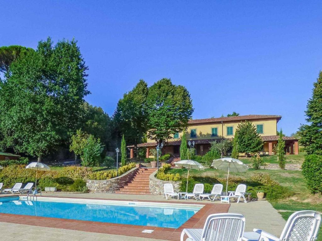 a resort with a swimming pool and chairs and a house at Lucca Cycling Holidays Il Tiglio Rooms in Lucca