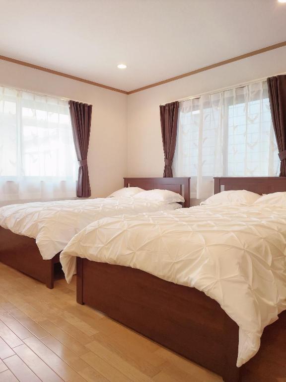 two beds in a bedroom with two windows at Young House in Matsudo