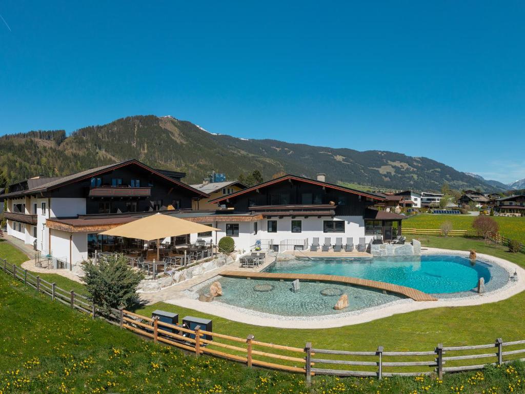 a resort with a large swimming pool with mountains in the background at Hotel Quehenberger in Maishofen