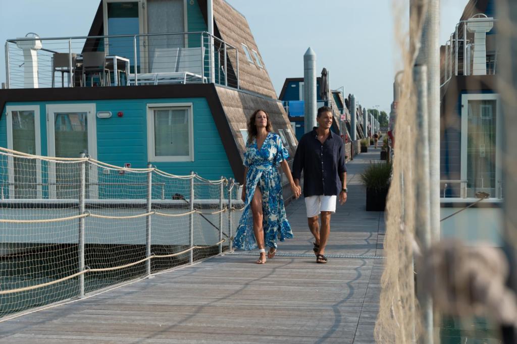 een man en een vrouw die over een promenade lopen bij Marina houseboat 2 pax in Lignano Sabbiadoro