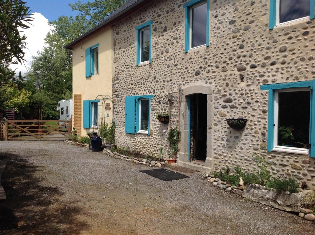 a stone house with blue windows and a driveway at Maison Mignaquy in Charritte-de-Bas