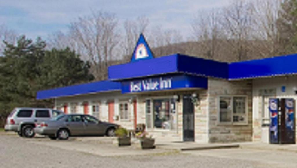 un distributore di benzina con macchine parcheggiate di fronte di Best Inn a Wellsville