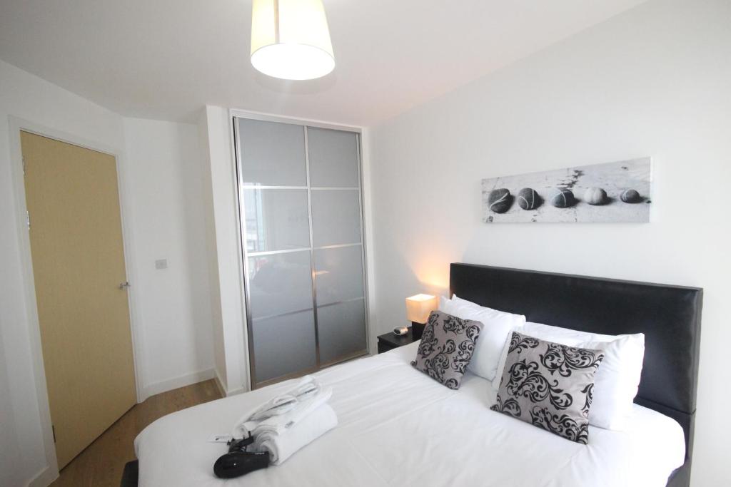 a bedroom with a bed with white sheets and pillows at Cotels at The HUB Serviced Apartments, Superfast Broadband, Central Location, Free Parking in Milton Keynes