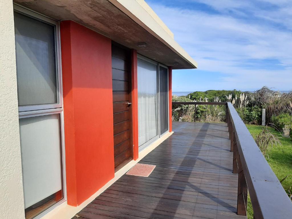 una casa con una puerta naranja y una pasarela en Delamar suites, en La Paloma