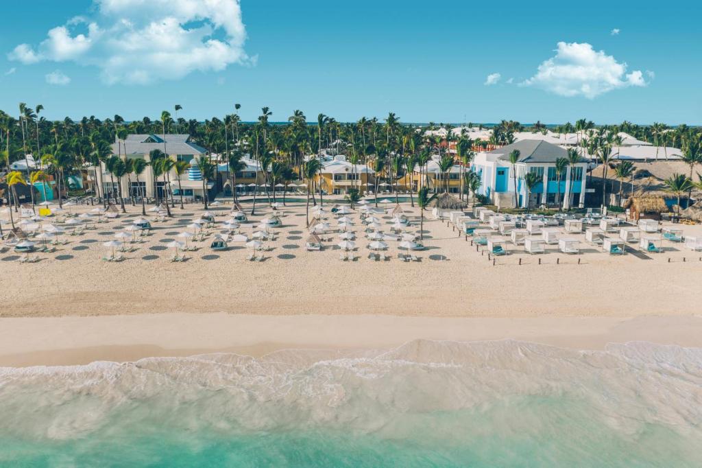a beach with chairs and umbrellas and palm trees at Coral Level at Iberostar Selection Bavaro - All Inclusive in Punta Cana
