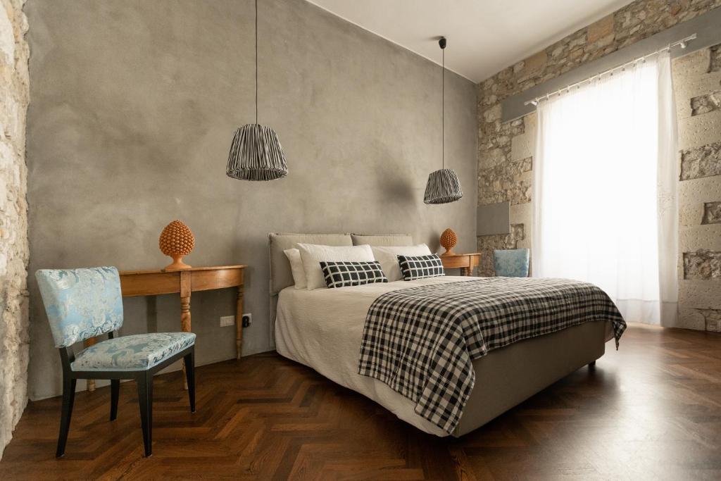 ein Schlafzimmer mit einem Bett, einem Tisch und einem Stuhl in der Unterkunft Suite San Tommaso - Ortigia Holidays in Syrakus