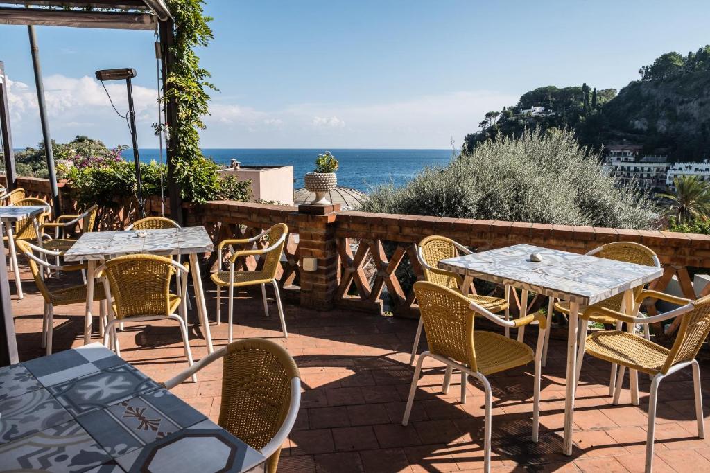 a patio with tables and chairs and the ocean at Hotel Villino Gallodoro in Taormina