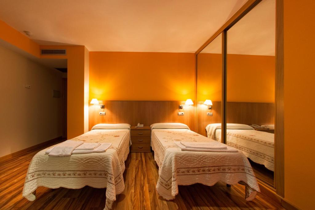 two beds in a room with a mirror at Hostal RIO SELMO in Ponferrada
