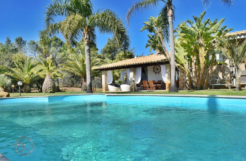 a swimming pool in front of a house with palm trees at Villa Palmetto in Forte Village