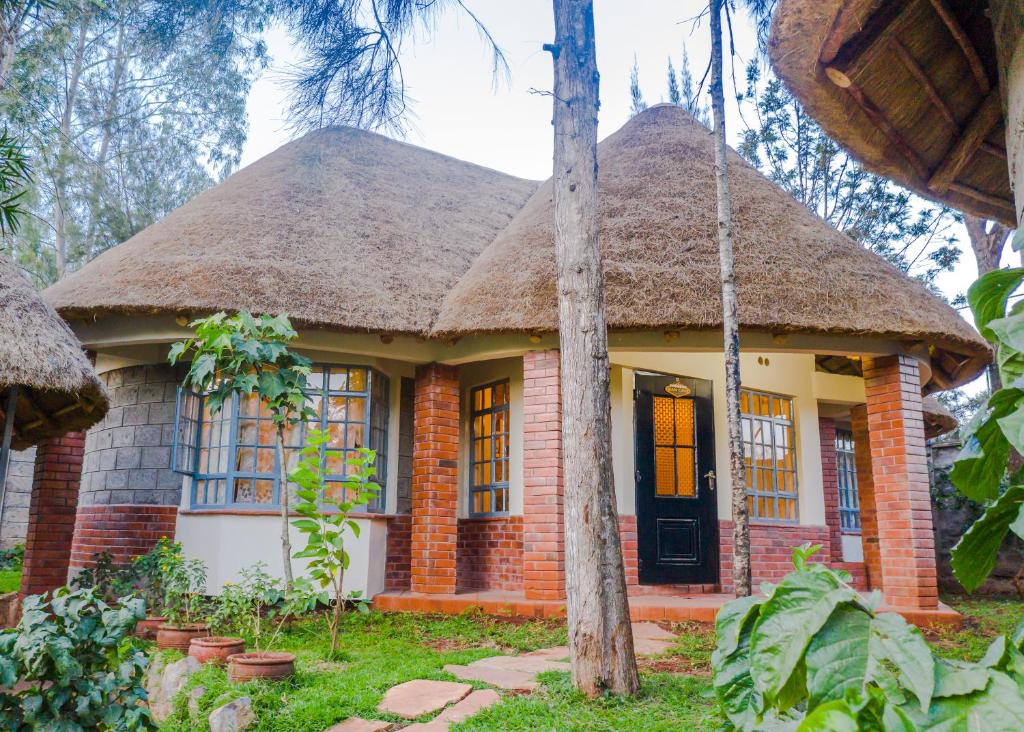 a small brick house with a thatched roof at Edaala Comfort - Cottage Rooms in Nairobi