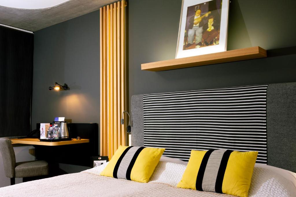 ein Schlafzimmer mit einem Bett mit gelben und schwarzen Kissen in der Unterkunft Martigny Boutique-Hôtel in Martigny-Ville