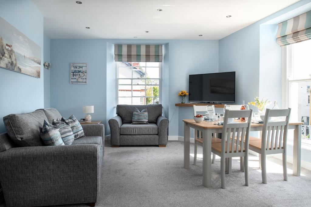 a living room with blue walls and a table and chairs at Abbey Road Boutique Holiday Apartment in Llandudno