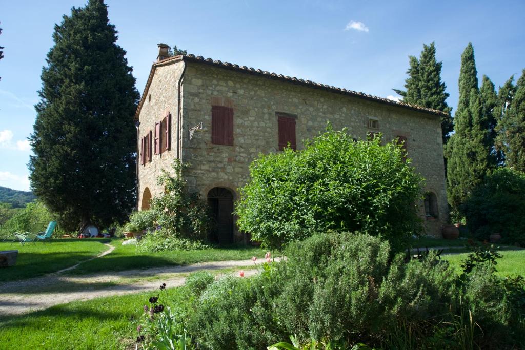un antiguo edificio de piedra en un campo con árboles en Agriturismo Il Caio, en Cetona