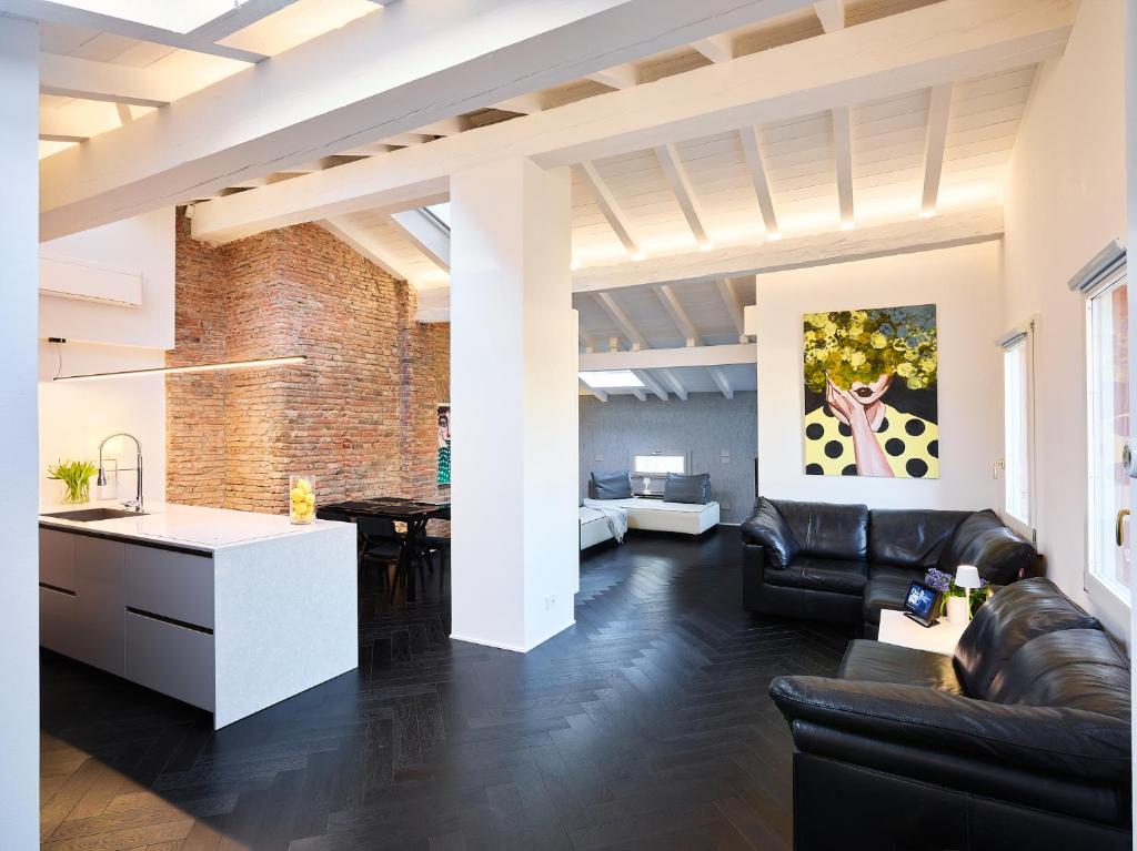 a living room with black leather furniture and a kitchen at OBERDAN SUITE Appartamento nel cuore di Bologna in Bologna