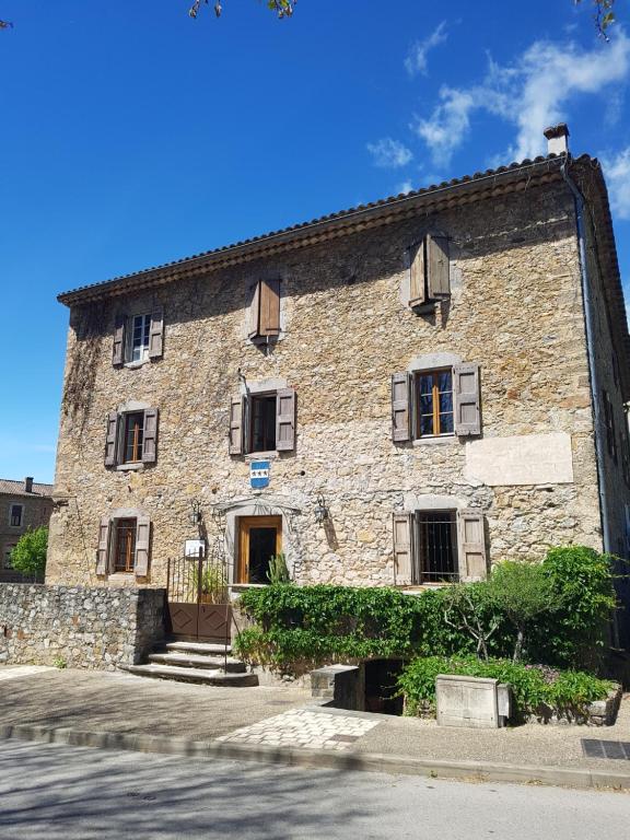 un antiguo edificio de piedra con ventanas y una puerta en MAS ELENA en Générargues