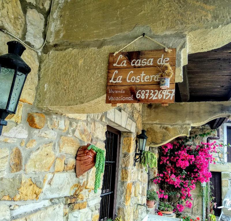 um sinal ao lado de um edifício de pedra com flores em La Costera en Liérganes, Cabarceno em Liérganes